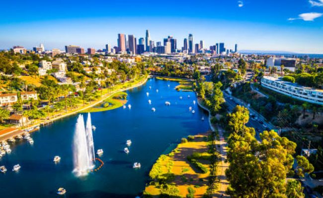 Aerial drone view above Los Angeles California 2019 over Echo Park Lake Pond Boats and traffic of the congested huge cityscape skyline of the downtown skyscrapers in the background August 2019 - Los Angeles California Echo Park With Fountain and Afternoon View of the Cityscape Skyline of the second largest city
